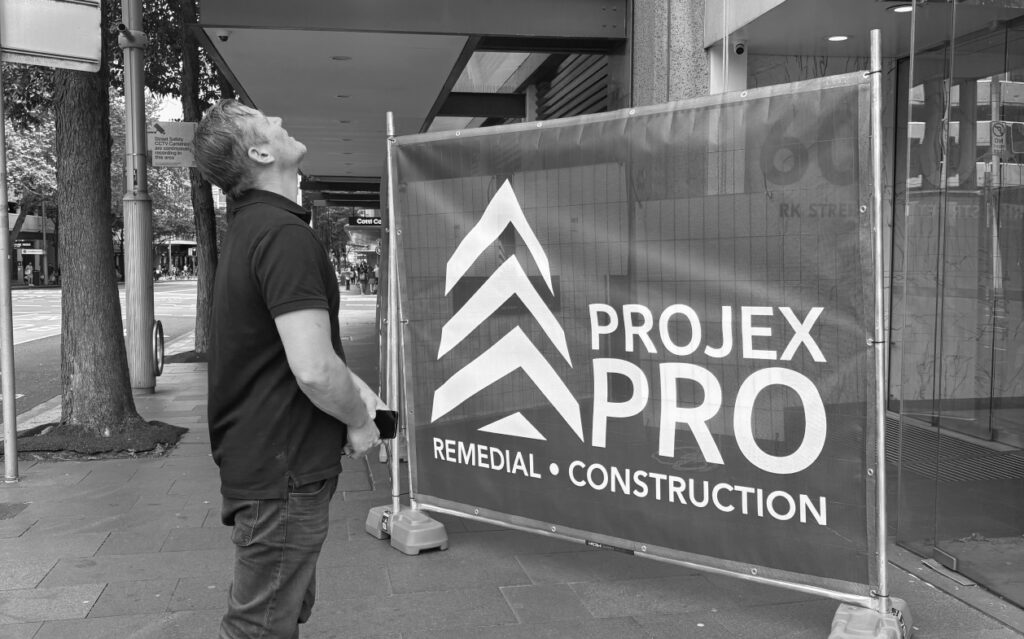 Projex Pro tradesperson on site behind branded glazing