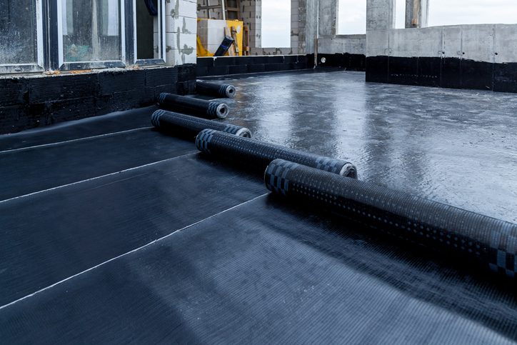 Freshly applied black waterproofing membrane on a balcony floor